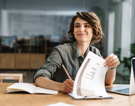Woman sitting at a desk reviewing papers in an office setting